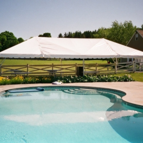 White tent set up outdoors by a pool