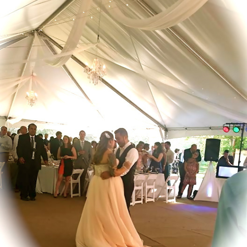 Bride and groom dancing underneath a white tent set up outdoors