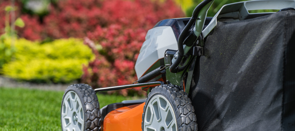 Orange push mower cutting grass on a lawn.